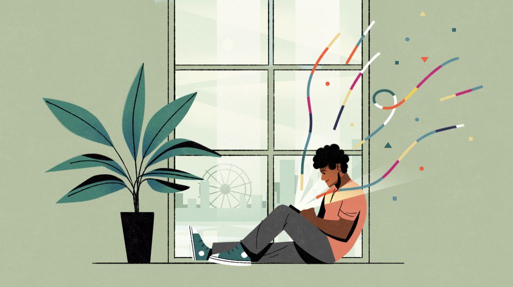 A woman sitting on the floor by a large window, using a device with colourful confetti-like streamers around her, in a bright, modern indoor setting.