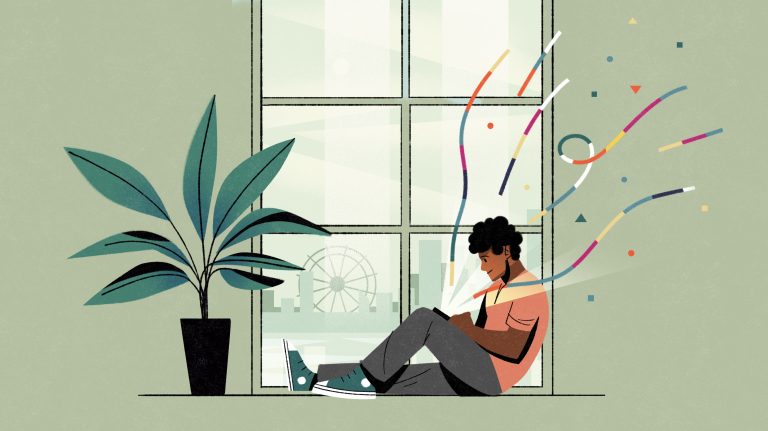 A woman sitting on the floor by a large window, using a device with colourful confetti-like streamers around her, in a bright, modern indoor setting.