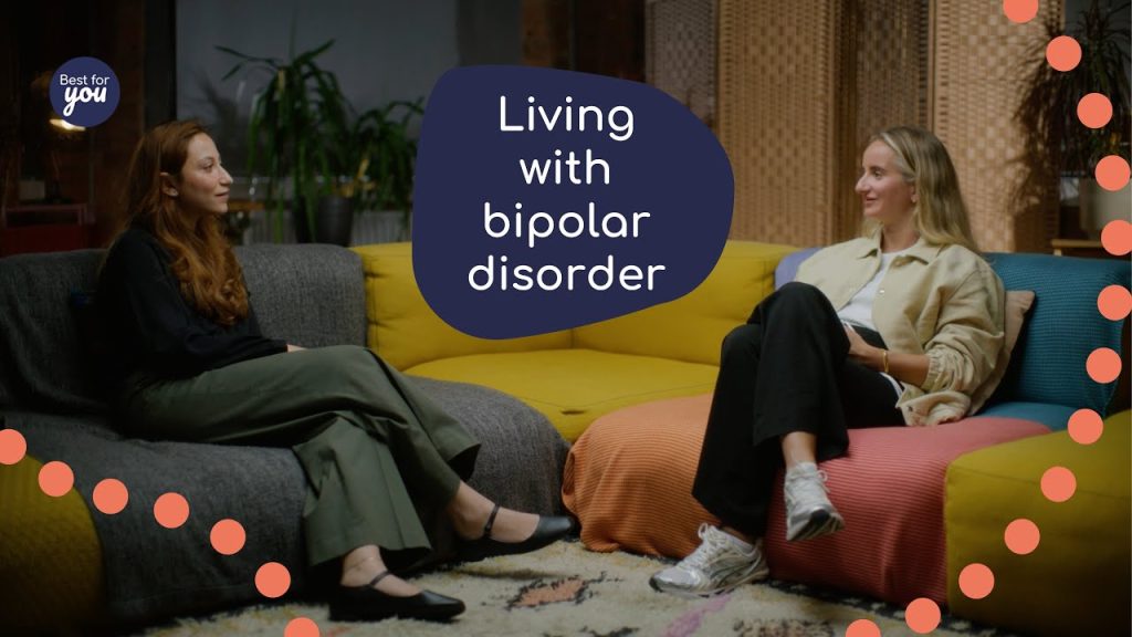 Living with bipolar disorder: two women having a supportive conversation in a comfortable, colourful therapy or support room.