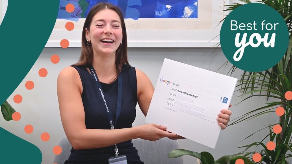 A woman smiling and holding a large Google search box sign at an indoor event, promoting digital literacy and online search skills.